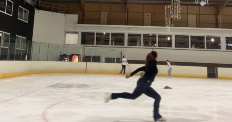 Adult figure skater on ice rink in axel entry position