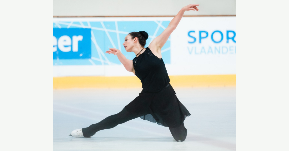 Female adult figure skater wearing basic black outfit in an artistic pose with arms outstretched, one knee on the ice and one outstretched leg.